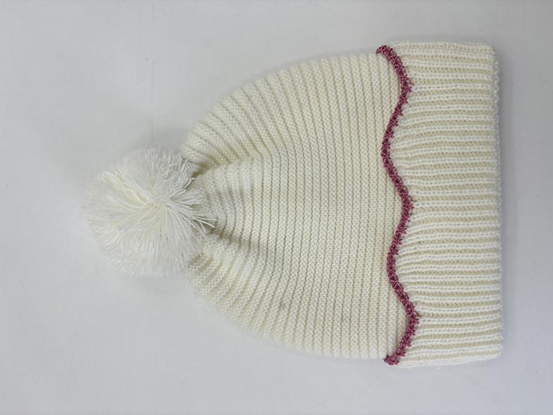 Krämvit stickad vintermössa med pompom och rosa sicksack-kantning.