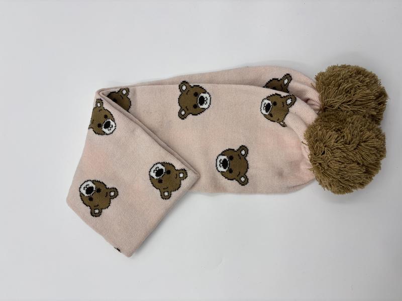 Rosa stickad halsduk med teddybjörnsmönster och stor olivgrön pompong i änden.