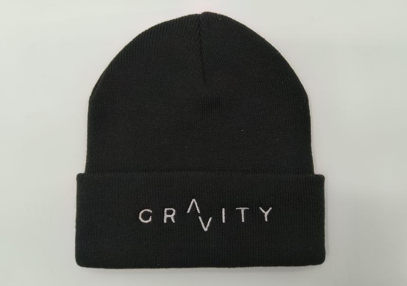 Svart ribbstickad mössa med uppvik och vit broderad GRAVITY-logotyp