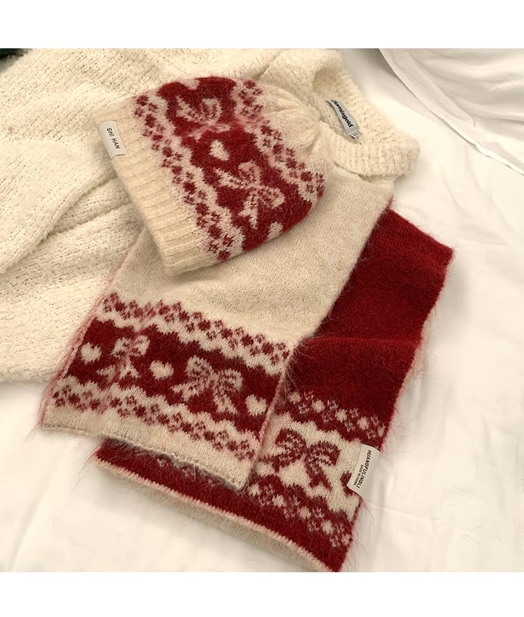 Röd och gräddvit stickad mössa och halsduk i Fair Isle-mönster med hjärtan och blommor mot vit bakgrund.