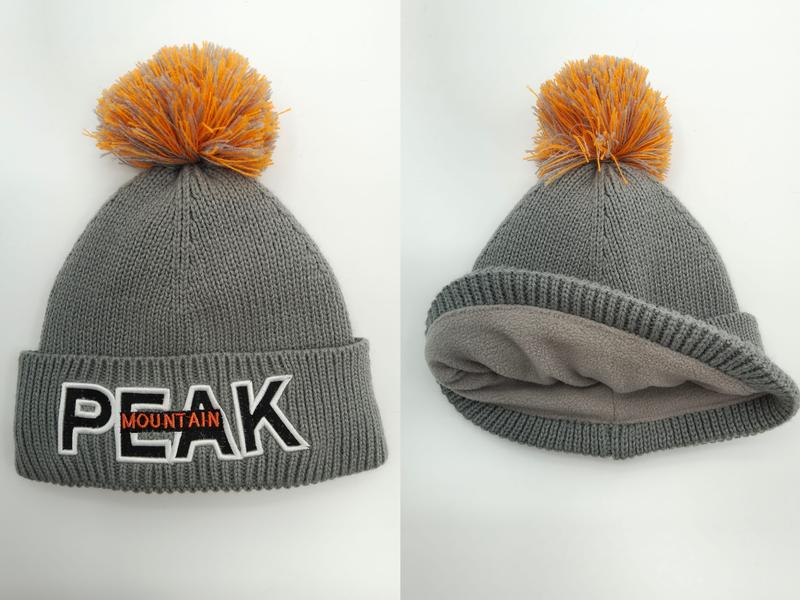 Grå stickad vintermössa med orange pompom