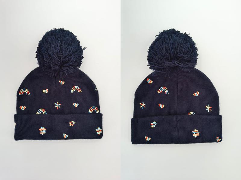 Marinblå stickad mössa med pompom och broderade regnbågar