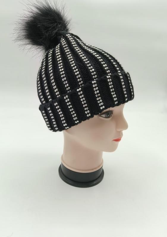 Svart ribbstickad vintermössa med silverrhinestone-ränder och svart konstpälspom-pom på mannekänghuvud.