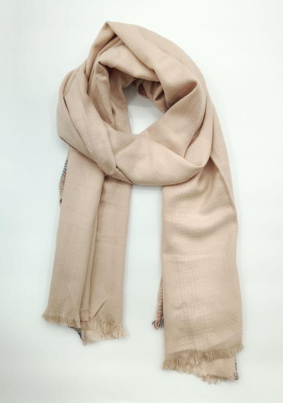 Beige kamelfärgad lättvävd sjal med knutna fransar på vit bakgrund.