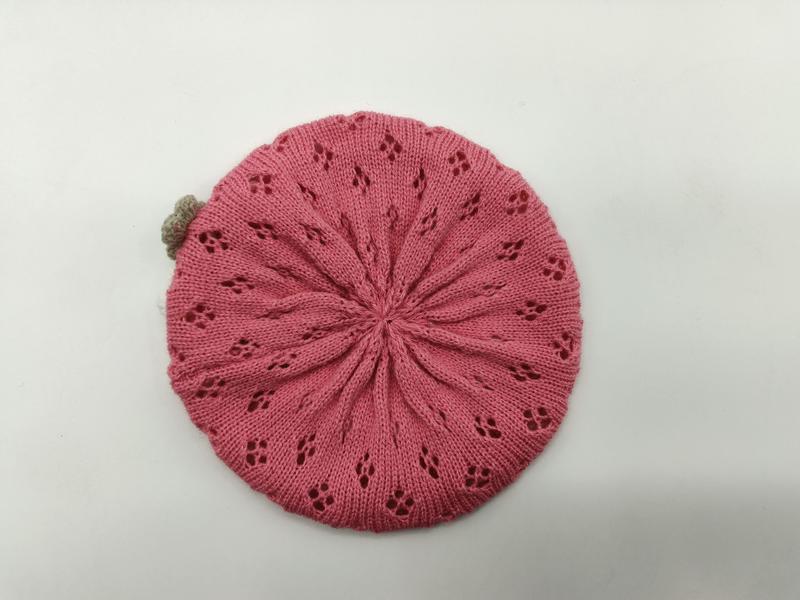 Rosa stickad basker med spetsigt blommönster och beige pompom
