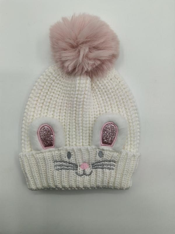 Vit grovstickad barnmössa med kaninöron och rosa pom-pom i konstpäls.