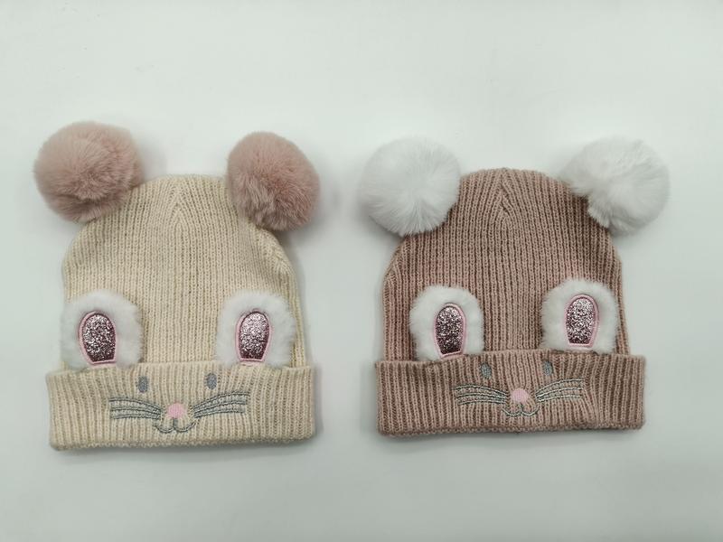 `Krämvit ribbstickad barnmössa med dubbla pompom-musöron i taupe och krämvitt.`