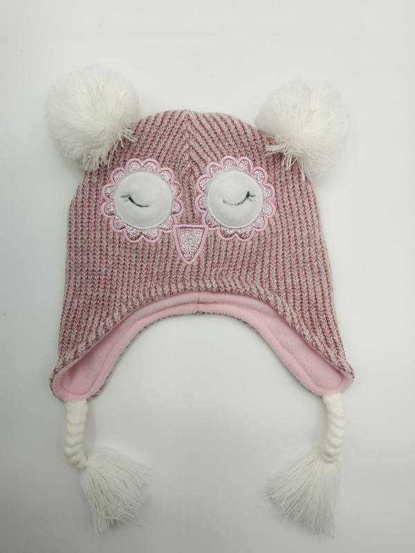 Rosa stickad ugglemössa för barn med pompomer och öronlappar.