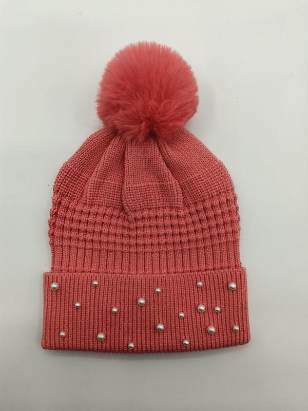 Korallrosa stickad mössa med pärldekorationer och pom pom uppe på toppen.