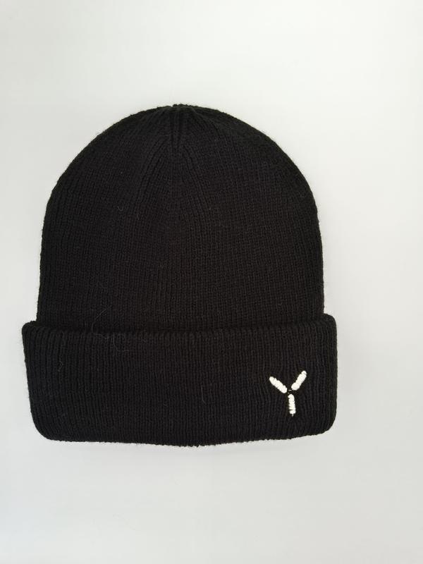 Svart ribbstickad mössa med vit broderad logotyp.