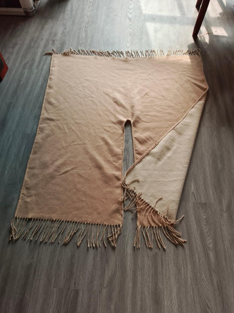 Beige och crämfärgad vändbar filt i vävt tyg med tvinnad franskant.