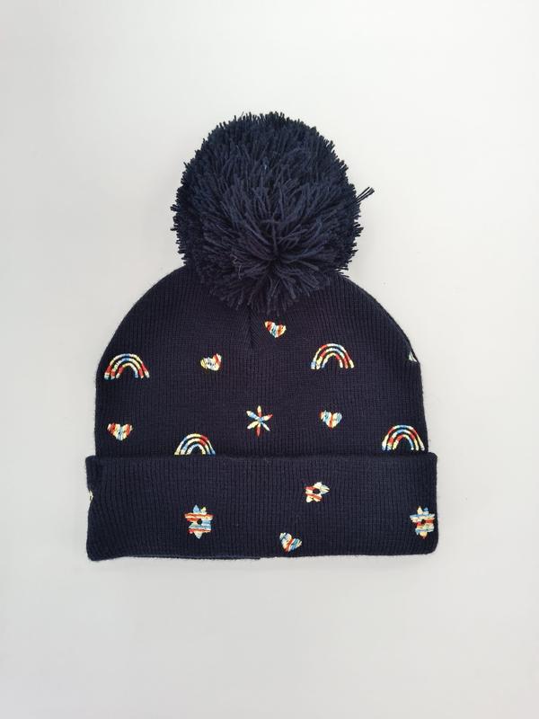 Marinblå ribbstickad mössa med stor pompom och färgglada broderade regnbågar
