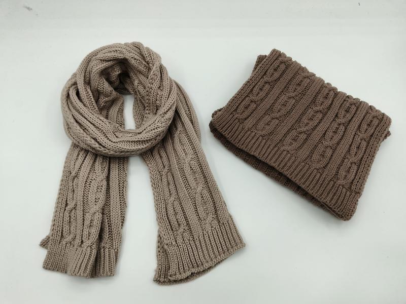 Beige kabelstickad scarf och brun tubhal i vikt läge mot vit bakgrund