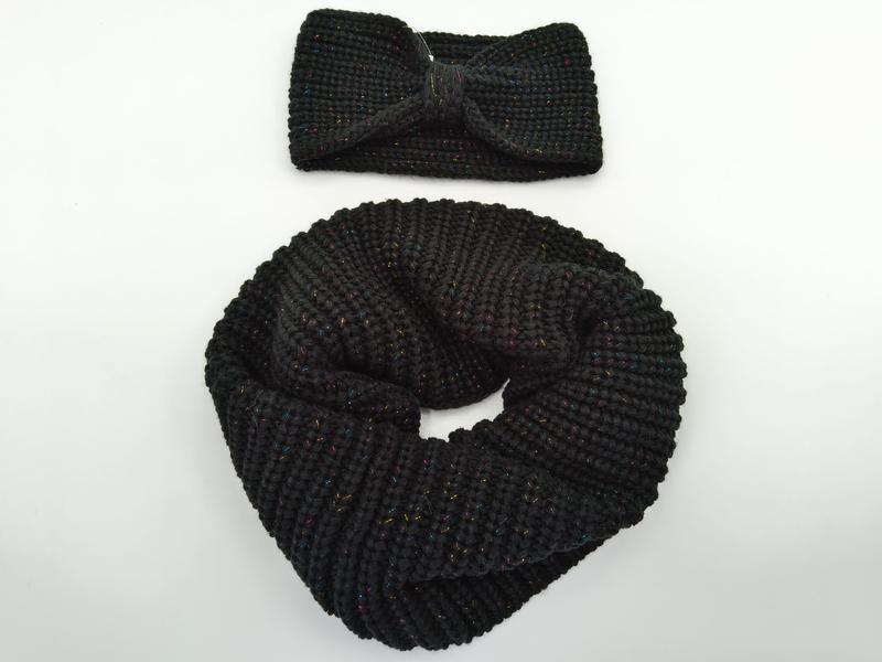 Svart stickad infinity-scarf bredvid matchande huvudband med glittrigt metalltråd i flera färger.
