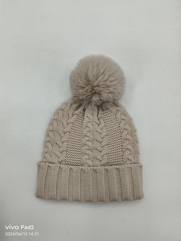Beige kabelstickad vintermössa med stor konstpälspom-pom och ribbad kant