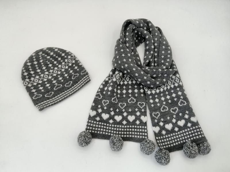 Grå och vit stickad mössa och halsduk med Fair Isle-hjärtmönster och pompomändar