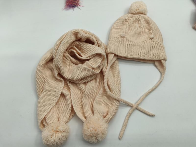 Krämvit stickad barnmössa med öronlappar och pompom