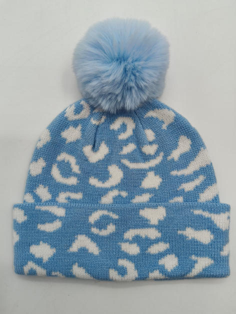 Ljusblå och vit leopardmönstrad stickad vintermössa med fluffig konstpälspom-pom på toppen.