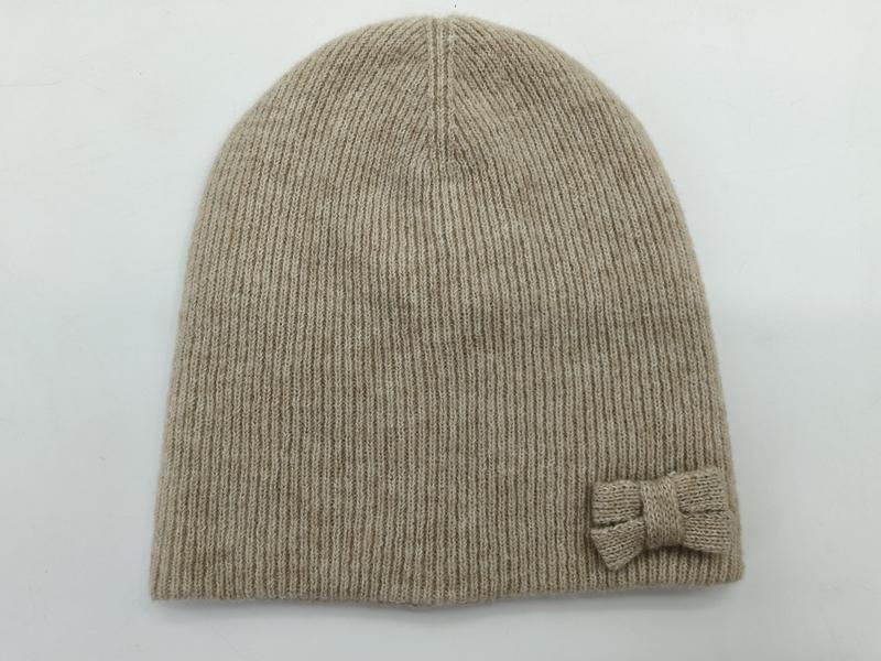 Beige ribbstickad mössa med liten stickad rosett på sidan