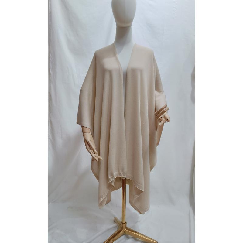 Beige stickad öppen poncho-cape i oversized modell med ribbad kantdetalj.