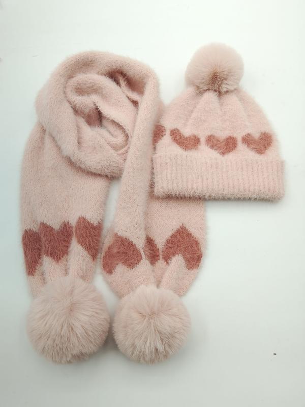 Rosa stickad mössa och halsduks-set med hjärtmönster och pompomer på vit bakgrund.