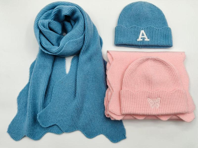 Blå stickad halsduk och rosa mössa med broderade bokstäver och fjärilar