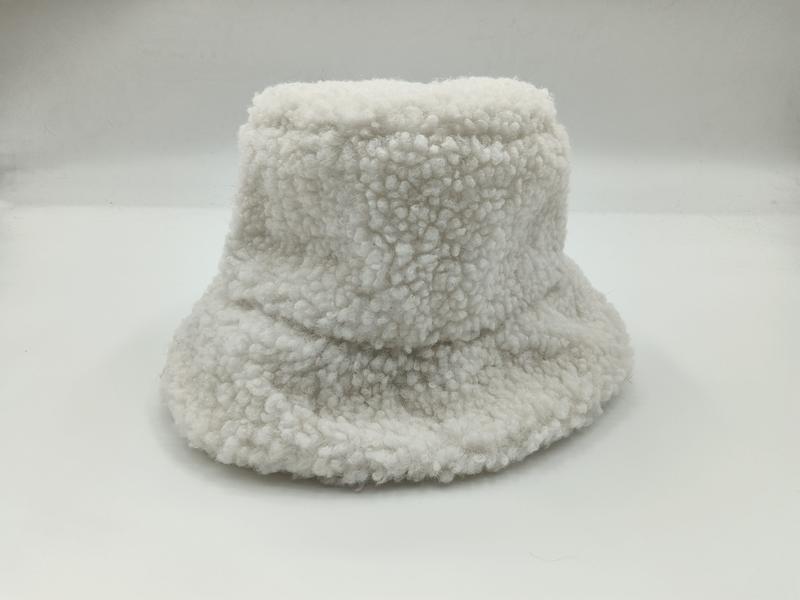 Vit sherpa bucket hat med bred brätte och gosig teddyfleece-textur mot vit bakgrund.