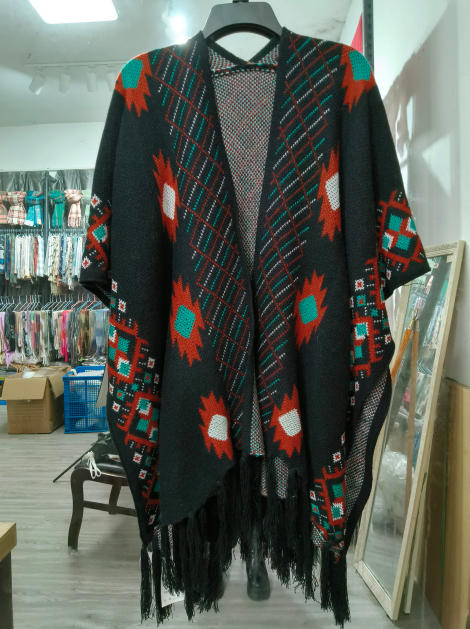 Svart stickad poncho med aztekiskt geometriskt mönster i teal