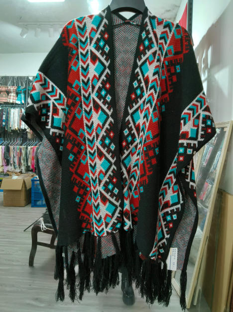 ""Svart stickad poncho med aztekiskt geometriskt mönster i rött