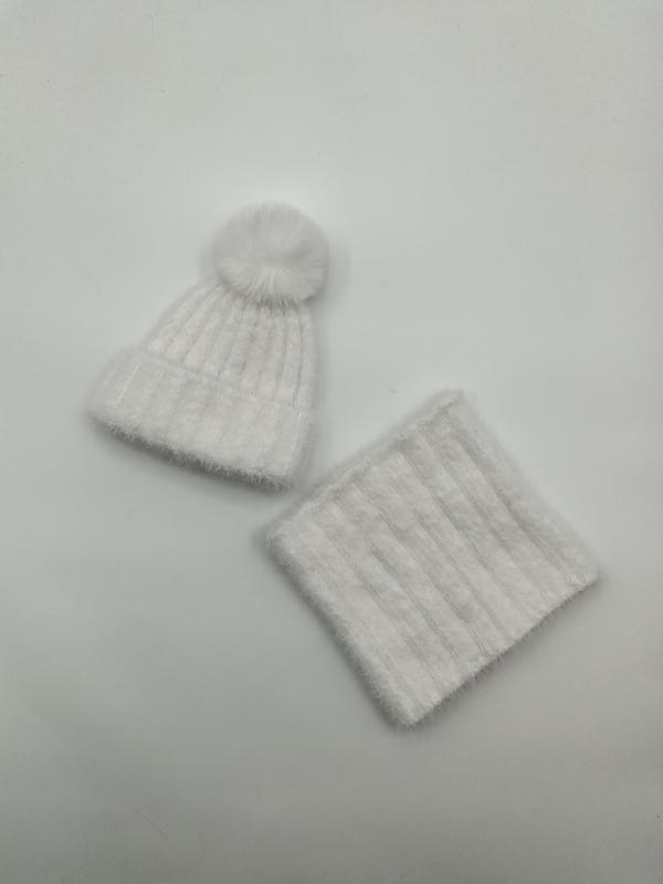 Vit fluffig ribbstickad vintermössa med pompom och matchande halsvärmande snood-set mot vit bakgrund.