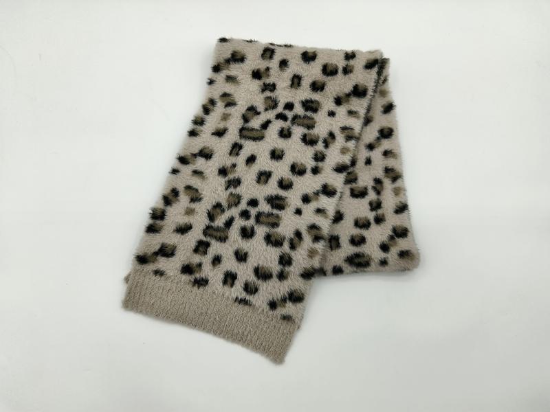 Veckad beige pälsimitationshalsduk med svart och brun leopardmönster mot vit bakgrund.