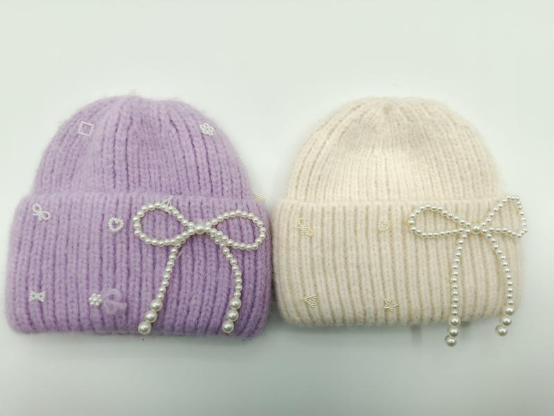 Lavendel och krämfärgad grovstickad mössa med pärlrosett och broderade motiv.