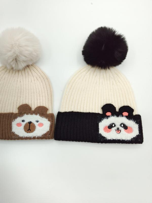 Två ribbstickade mössor med pompom – en beige björn och en vit panda – med applikationer och matchande pompombollar.