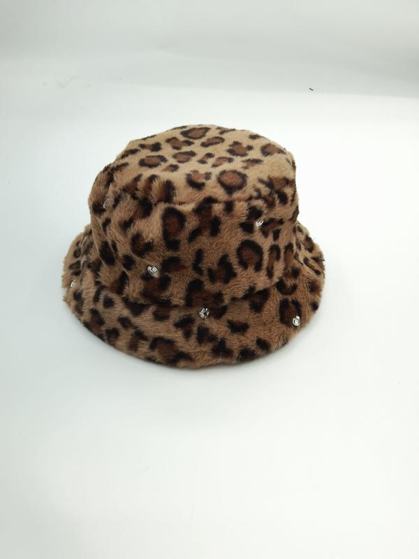 Fluffig leopardmönstrad hink hatt i beige och brun med kristallstrassdetaljer mot vit bakgrund.