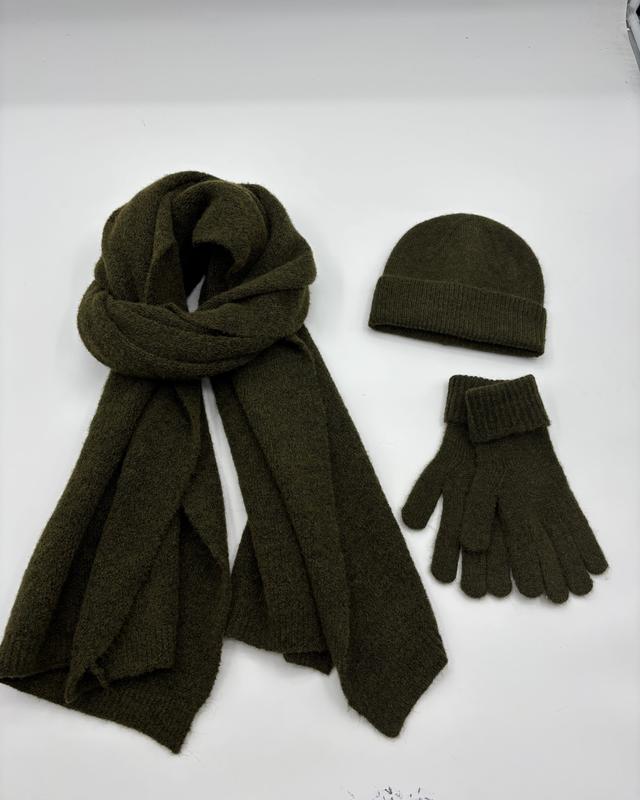 Olivgrönt stickad vinterset med oversized halsduk, ribbad mössa och matchande handskar mot vit bakgrund.