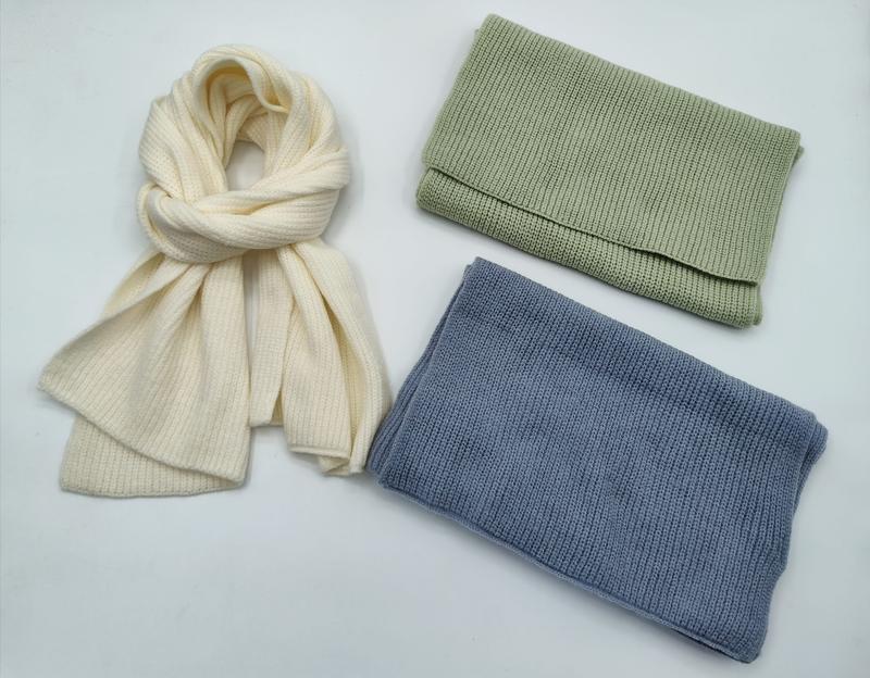 Ribbstickad halsduk och neckwarmer i grädde, salviagrön och stålblå mot vit bakgrund.